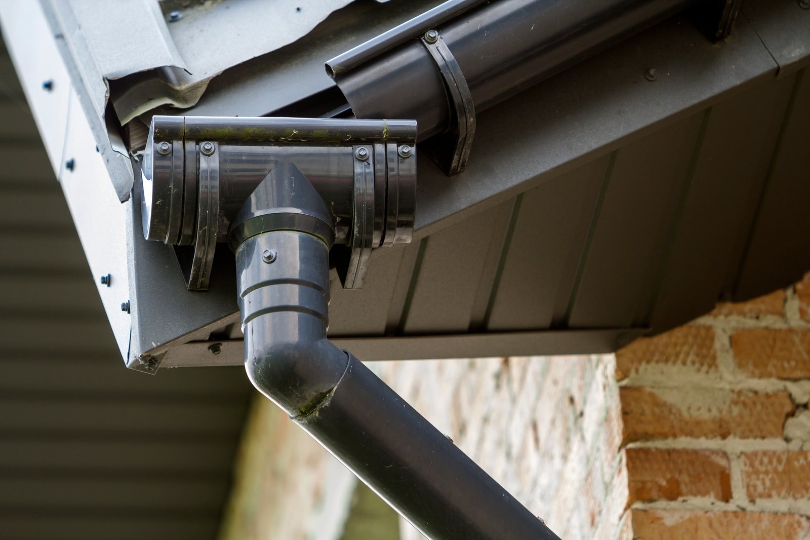 Close-up detail image of a corner of new built brick cottage house roof with steel gutter rain