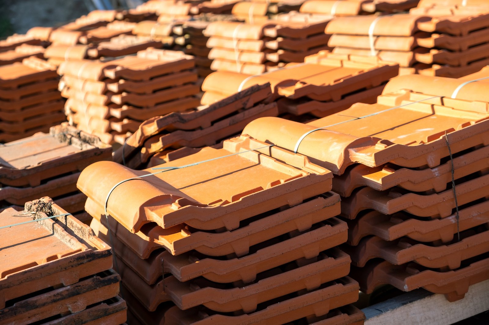 Stacks of yellow ceramic roofing tiles for covering residential building roof under construction